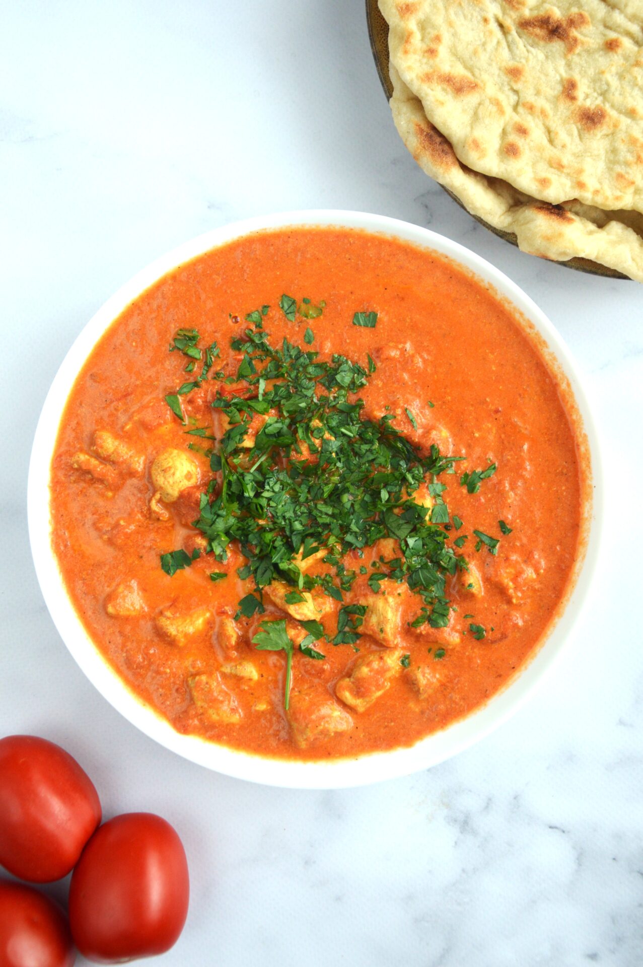 Curry butter chicken w białej misce z chlebkami naan